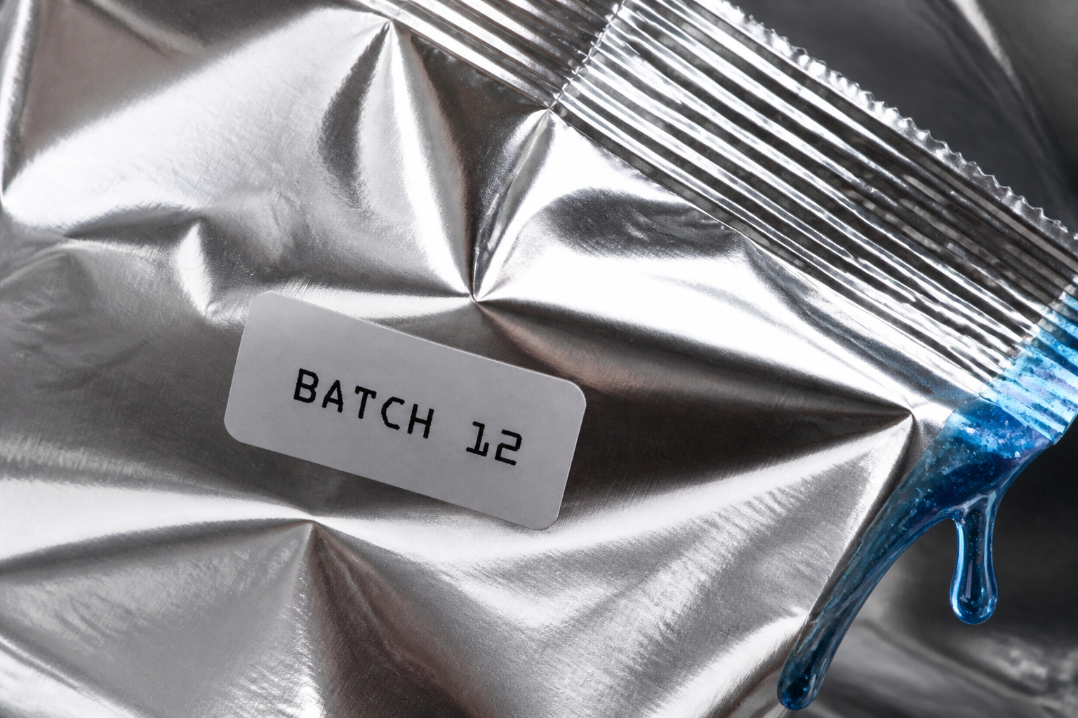 Macro batch-code sticker and foil fold with a blue raspberry drip